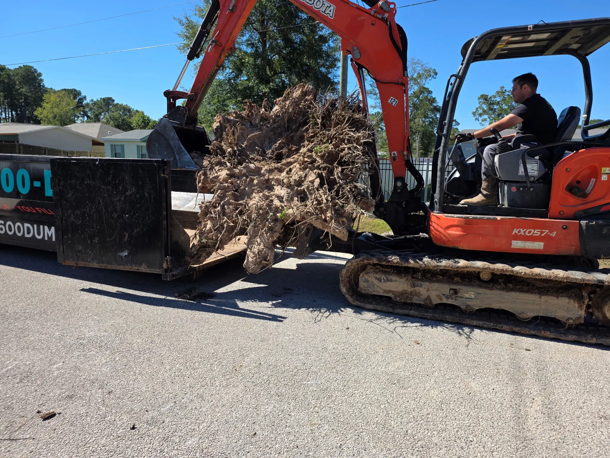 936-600-DUMP Kubota excavator loading debris into roll-off dumpster during land clearing in Montgomery County TX