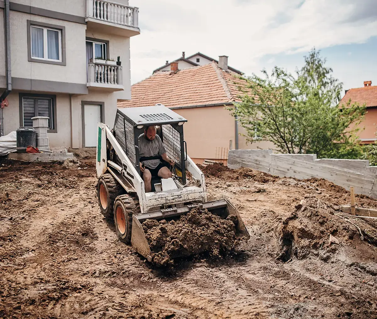 Skid-steer loader moving dirt at residential construction